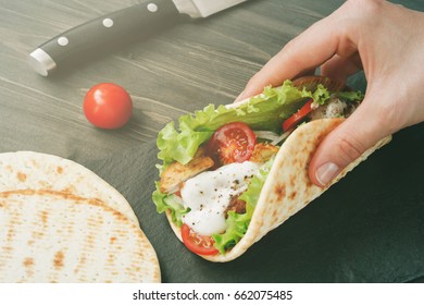 Hand Holding Mexican Fajita Wrap With Chicken Meat And Vegetables