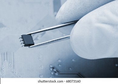 Hand Holding Microchip With Pair Of Tweezers