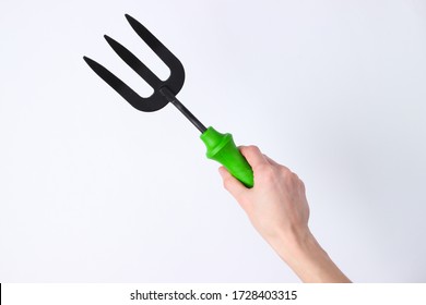 Hand Holding Mini Garden Fork Isolated On White Studio Background.