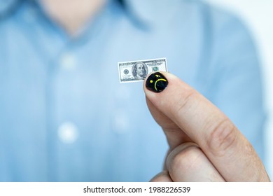 Hand holding miniature dollar note. the concept of dollar inflation. a small salary for an employee. man with painted nails. Design of male nails. men manicure.