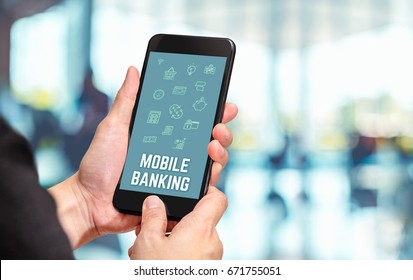 Hand holding mobile with Mobile banking word and features icon with blur office counter background,Digital Lifestyle concept.