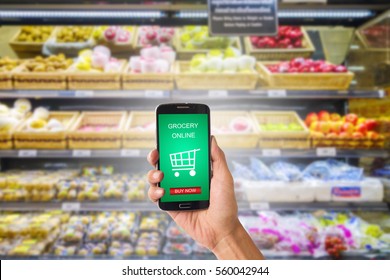 Hand holding mobile with grocery online on screen with blur supermarket background