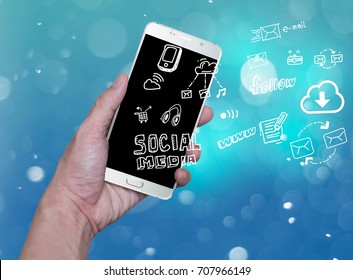 hand holding mobile phone with cloud computing with blue background .Hand holding smartphone with hand drawn media icons and symbols concept style. - Powered by Shutterstock