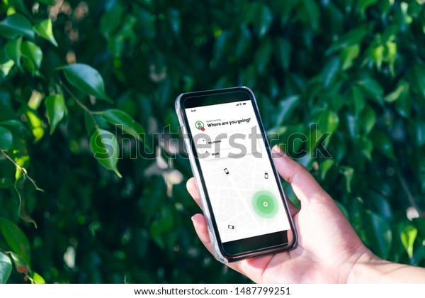 Hand holding mobile phone device outdoors to book\
taxi using ride hailing app - Woman booking internet taxi service\
using smartphone device for journey to work - cab, commuting and\
lifestyle concept