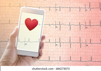 Hand Holding Mobile Phone With Red Heart On Echo Cardiogram Graph Background.