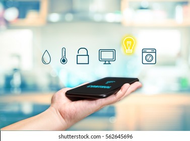 Hand Holding Mobile With Smart Home Control Icon Feature With Blur Kitchen Background,Digital Lifestyle Concept