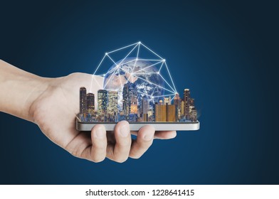 Hand holding mobile smart phone with modern buildings global network connection technology hologram. Element of this image are furnished by NASA - Powered by Shutterstock