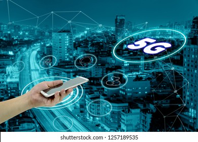 hand holding mobile smart phone with cityscape,5G network interface and icon concept