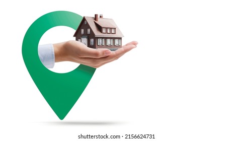 Hand holding a model house and location pin, real estate concept, White background
