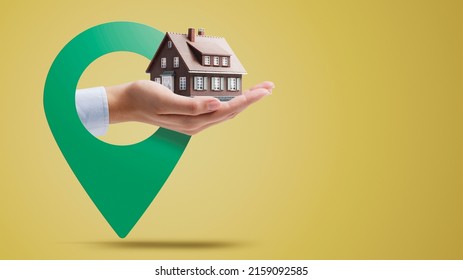 Hand Holding A Model House And Location Pin, Real Estate Concept