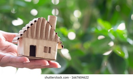 Hand holding  model  house made of paper, The green background of the tree is shady. Concept Buying and Selling Used Homes.