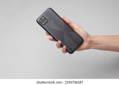Hand holding modern  back side smartphone with cameras on gray background - Shutterstock ID 2196736187
