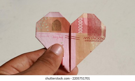 Hand Holding Money Folded In The Shape Of Love