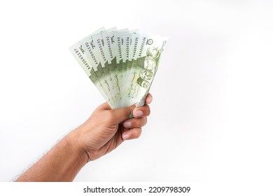 Hand Holding Multiple Pakistani Bank Notes Known As Pakistani Currency Isolated With White Background