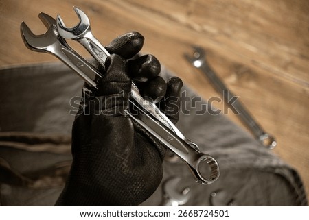 Hand holding multiple wrenches while preparing for mechanical work in a workshop setting