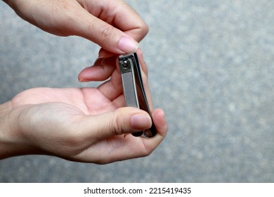 Hand Holding Nail Clippers And Cutting Thumb Nail.