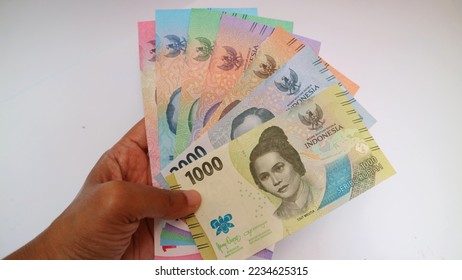 Hand holding New Indonesian rupiah banknotes or IDR on white background. the official currency of Indonesia. Indonesian Rupiah. Emission year 2022
