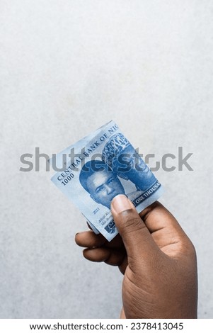 Hand holding the new Nigerian 1000 Naira notes on a white surface, Hand holding Nigeria's new currency