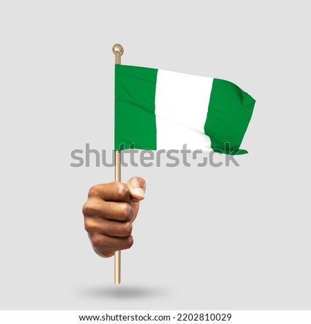 Hand holding Nigerian national flag isolated on gray background