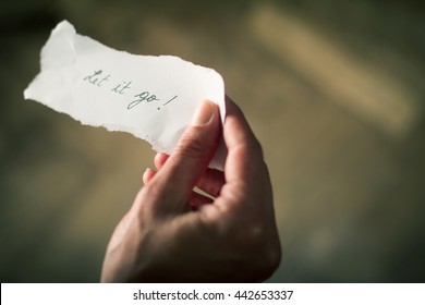 Hand Holding A Note Of Paper With The Message Let It Go Written On It