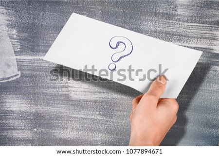 Hand holding a note written a question