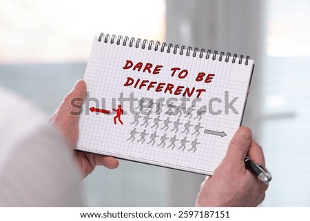 Hand holding a notepad with dare to be different concept