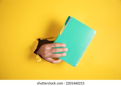 Hand Holding Notepad On Yellow Background