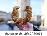 Hand holding obwarzanek krakowski prezel on Cracow Main Market Square. St. Mary