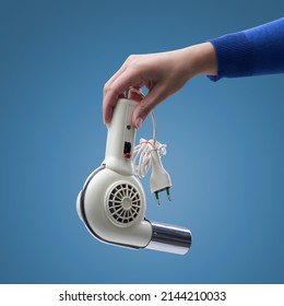 Hand Holding An Old Broken Appliance, Isolated On Blue Background