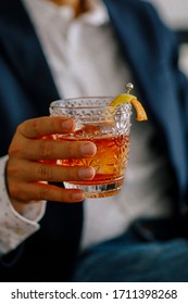 Hand Holding An Old Fashioned Cocktail With Orange Garnish