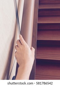 The Hand Holding On To A Wooden Banister. Closeup Of Senior Using The Wooden Railing Of Stairs To Go Upstairs At Home.