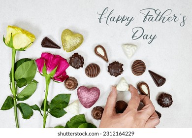 hand holding one piece of premium chocolate sweets on marble background with roses flowers and happy father's day text  - Powered by Shutterstock