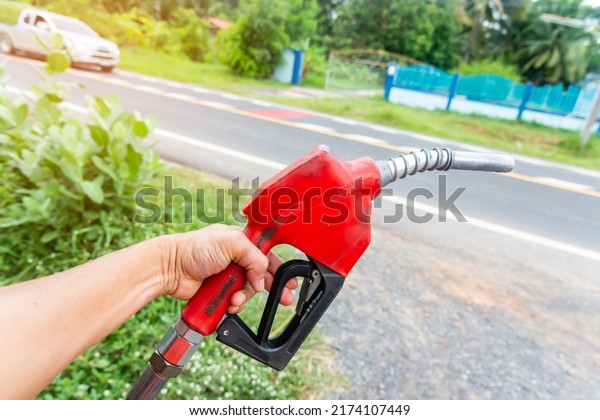 Hand holding orange\
fuel nozzle.Gas pump service and refuelling car at the station oil.\
oil crisis concept.