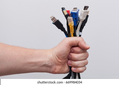 Hand holding out a bunch of computer cables with different connectors