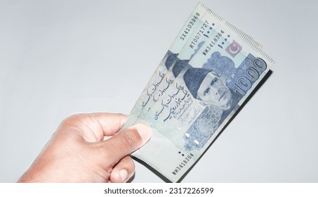 hand holding Pakistani currency banknotes on white background. 1000 rupees banknotes holding in hand