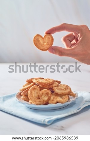 Hand holding Palmier puff pastry cookie or homemade orejitas.
