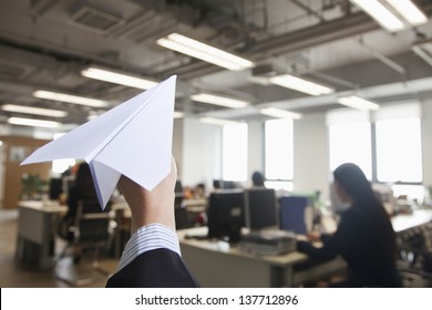 Hand Holding Paper Airplane In Office