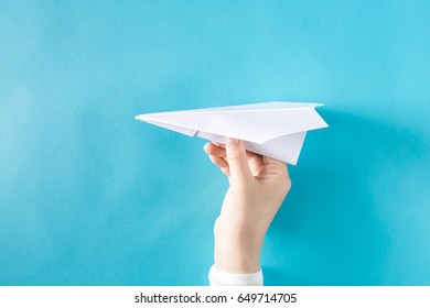 Hand Holding A Paper Airplane On A Blue Background