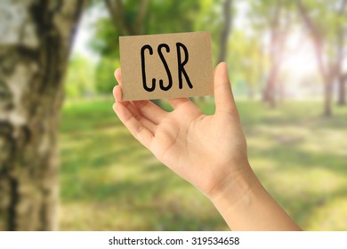 Hand Holding A Paper Card With Corporate Social Responsibility (CSR) Concept On Abstract Nature Background