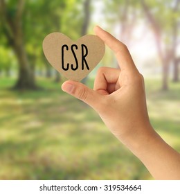 Hand Holding A Paper Card With Corporate Social Responsibility (CSR) Concept On Abstract Nature Background