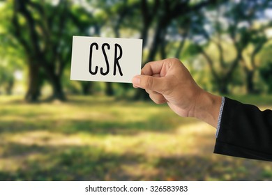 Hand Holding A Paper Card With Corporate Social Responsibility (CSR) Concept On Abstract Nature Background