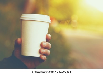 Hand Holding Paper Cup Of Coffee On Natural Morning Background