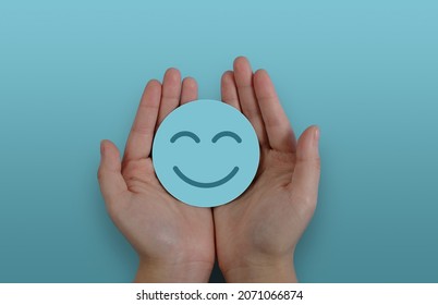 Hand holding paper cut smile face, positive thinking, mental health assessment , world mental health day concept - Shutterstock ID 2071066874