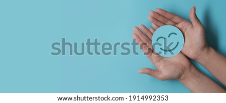 Hand holding paper cut smile face, positive thinking, mental health assessment , world mental health day concept
