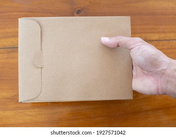 A hand holding a paper envelope