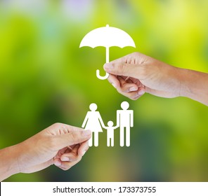 Hand holding a paper family and umbrella on green background - Powered by Shutterstock