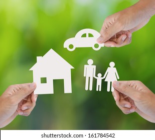 Hand Holding A Paper Home, Car, Family On Green Background, Insurance Concept