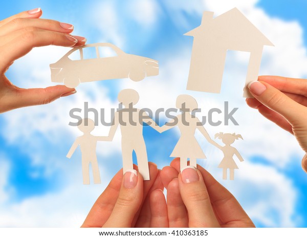 Hand holding a paper home, car, family on blue\
sky background