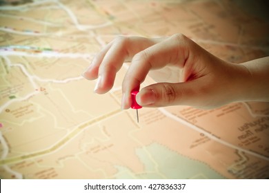 Hand Holding Paper Pin On Blur Road Map