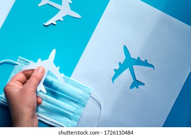 Hand Holding Paper Plane Over Face Mask Takes It From Shadow To Light. Air Travel Resumes After Travel. Vacations Stopped, Borders Closed Due To Coronavirus Pandemics. Restart Flying, End Quarantine.